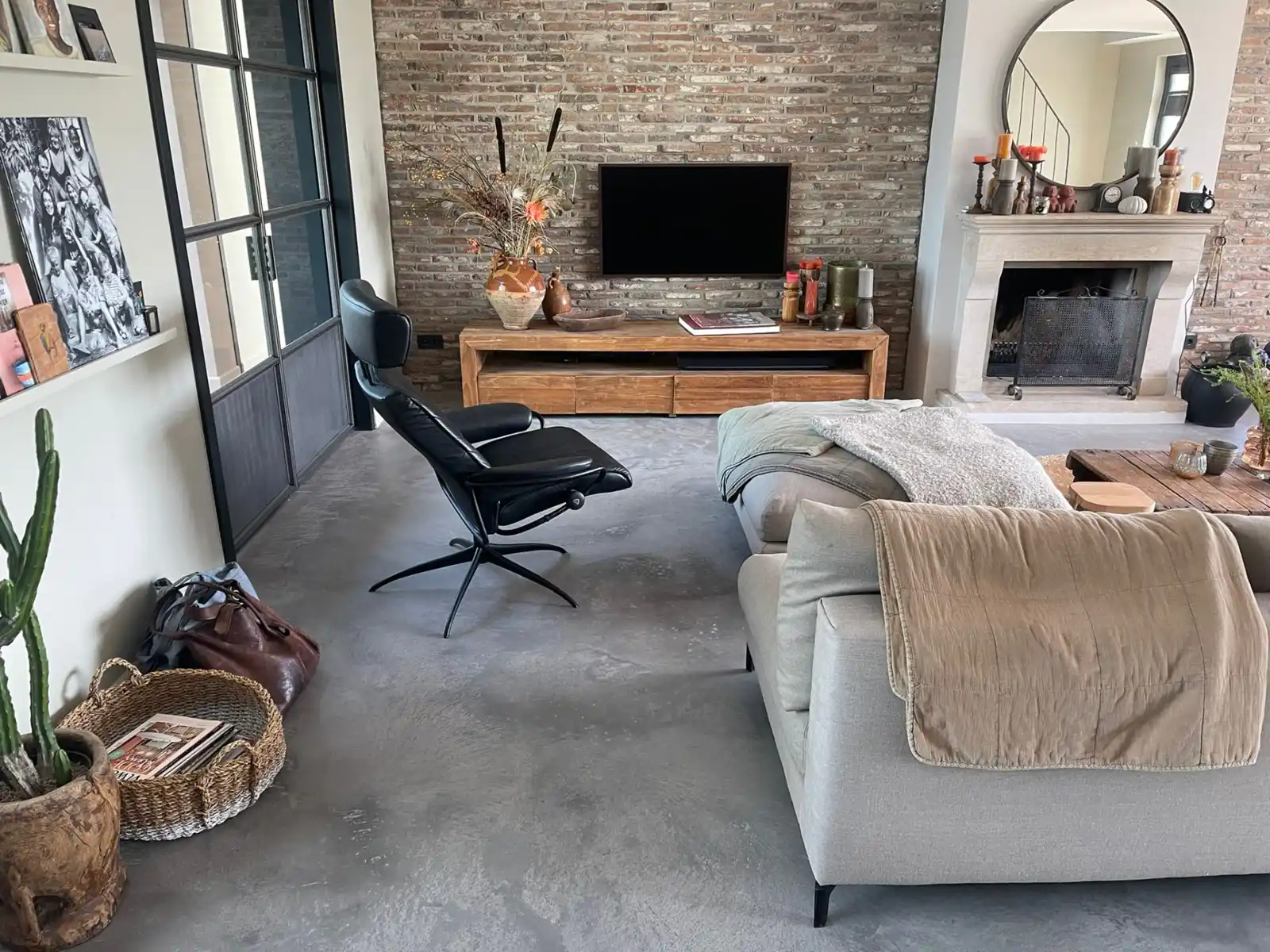 Grijze Architop vloer in een woonkamer met bakstenen wand en open haard