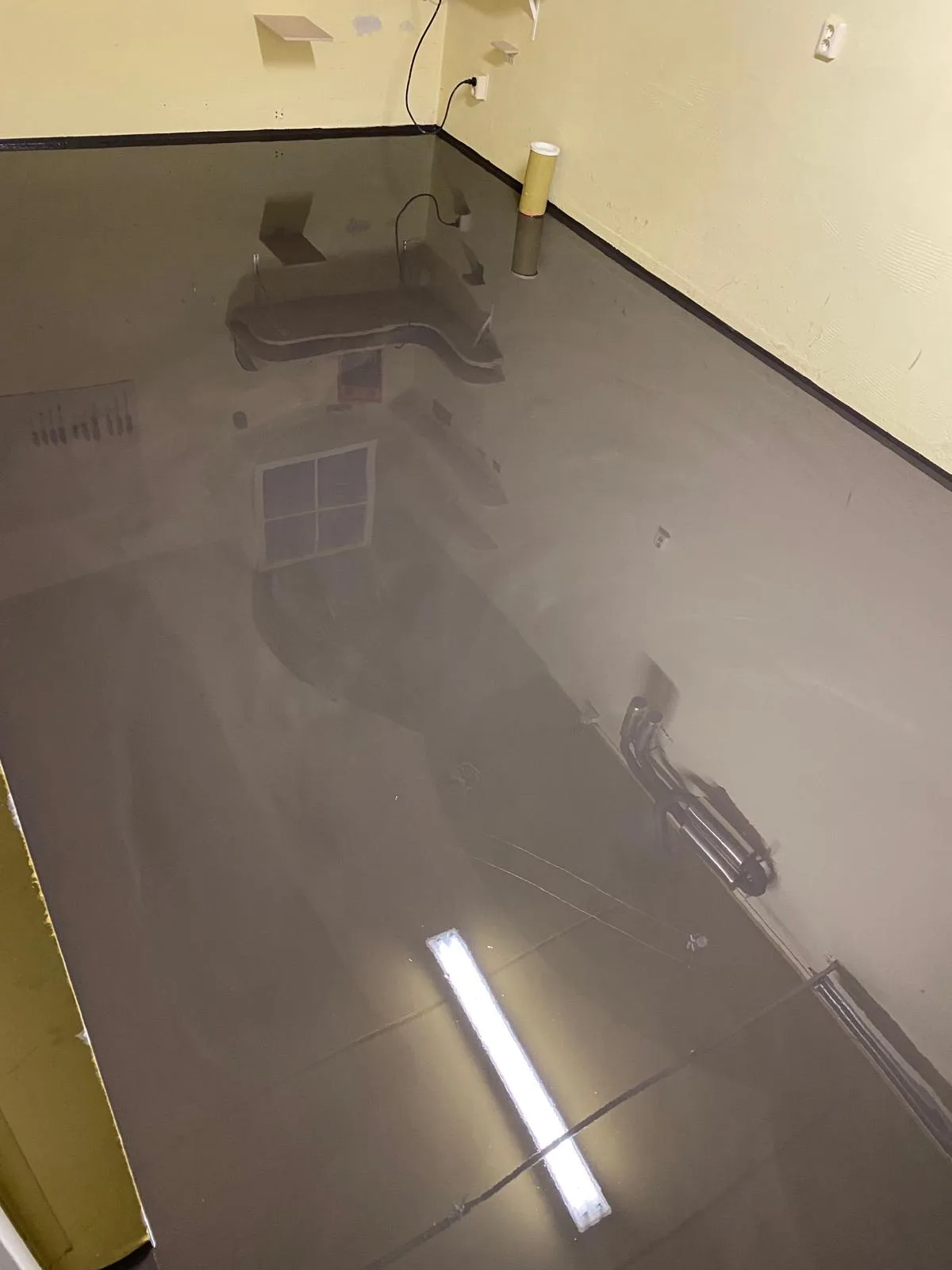 Spiegelende grijze epoxygietvloer in een net opgeleverde ruimte