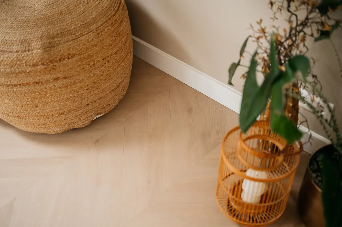 Lichte pvc houtlook vloer met jute poef en rieten lantaarn