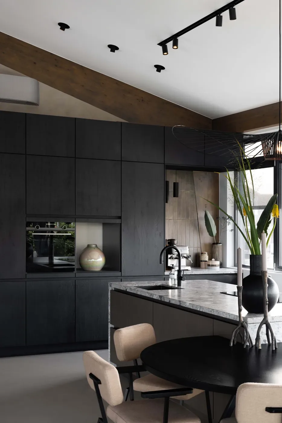 Grijze gietvloer in een zwarte keuken met eettafel