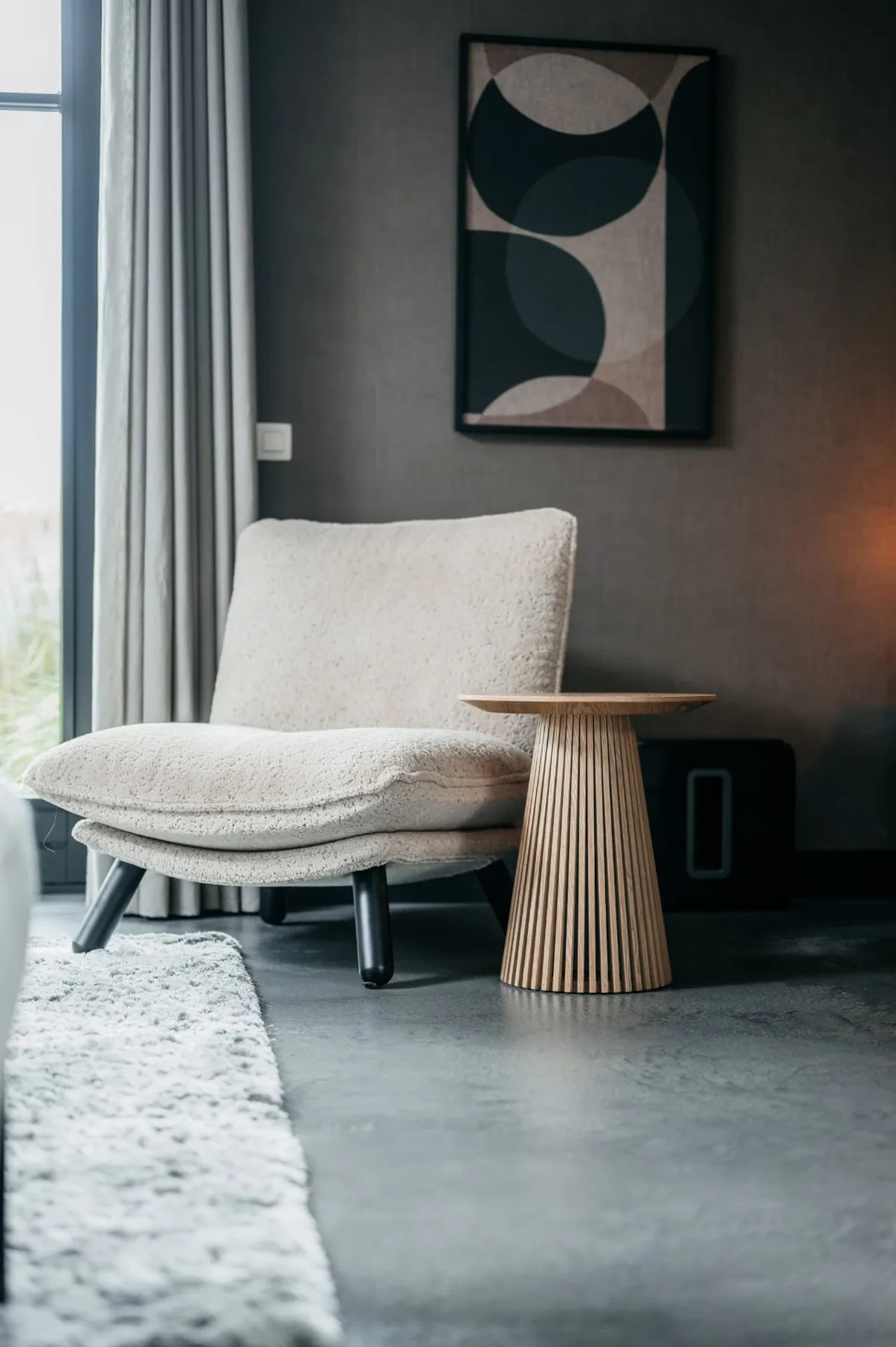 Strakke grijze Architop vloer bij een fauteuil en houten bijzettafel