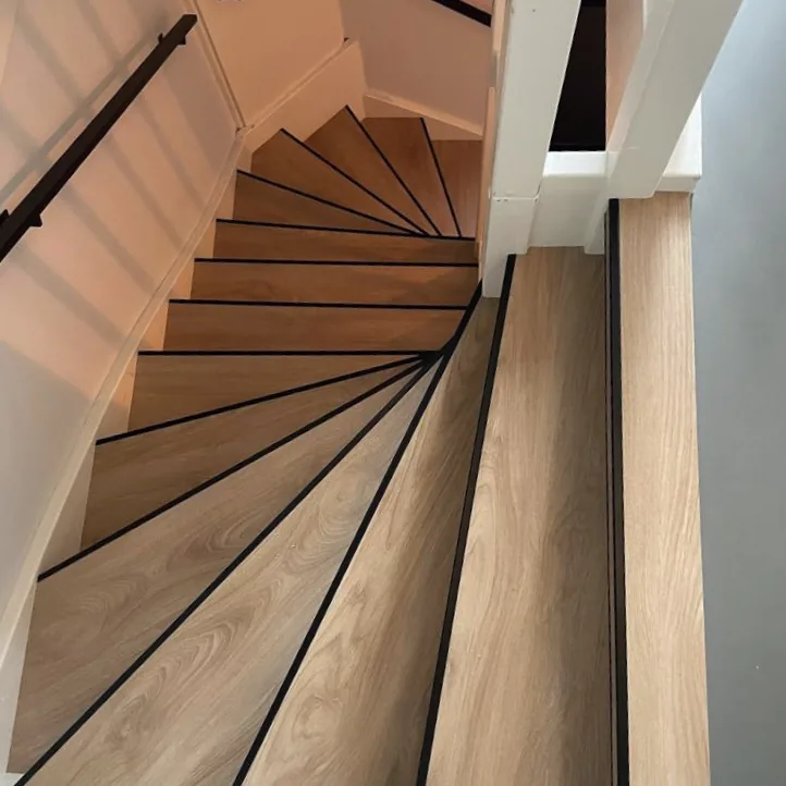 Gedraaide trap met lichte houtlook treden en zwarte antislipstrips