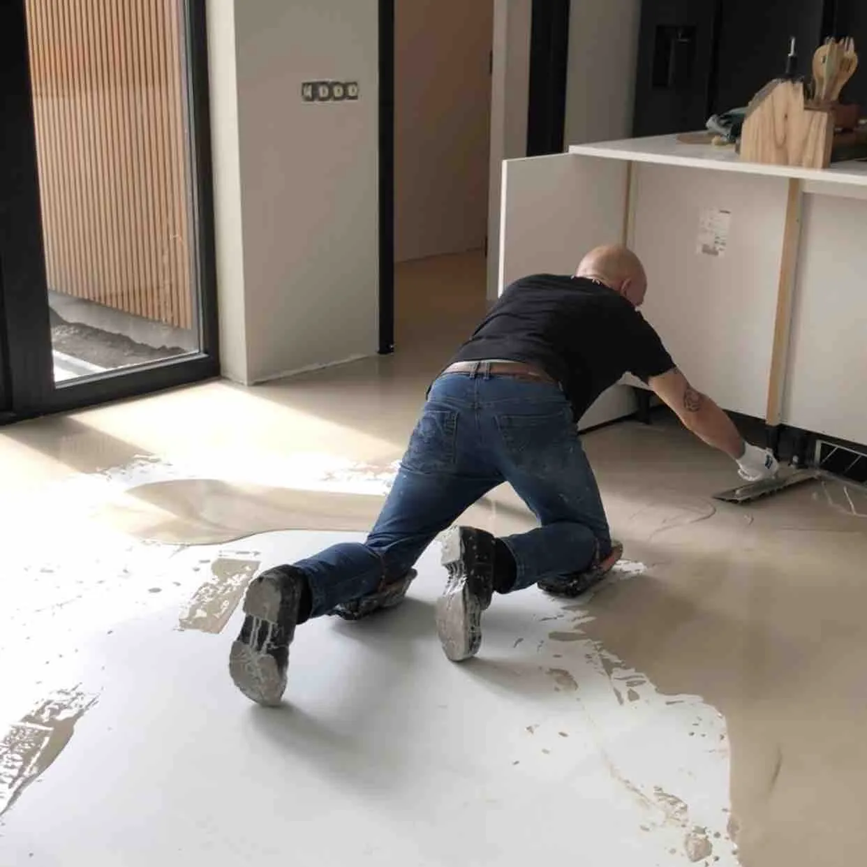 Vloerlegger van M2 Vloeren brengt knielend een gietvloer aan