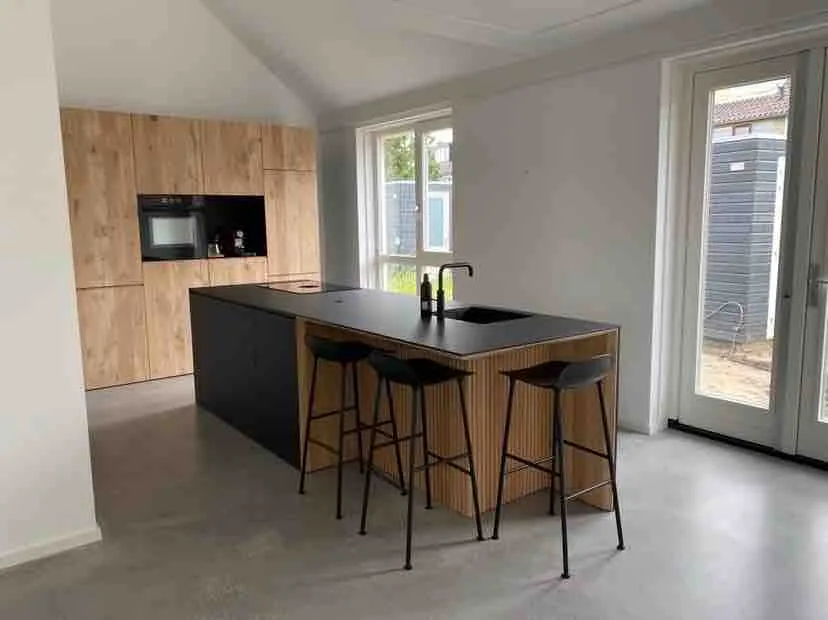 Pas gelegde gietvloer in een lege nieuwbouwkeuken met houten keukenwand